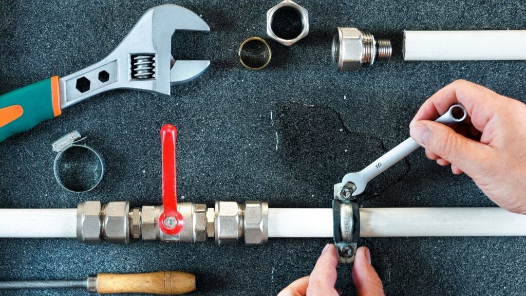 Plumber repairing a pipe valve with an adjustable wrench in Port Orange