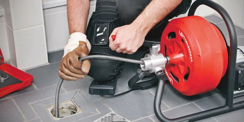 Plumber using a drain-cleaning machine in Port Orange