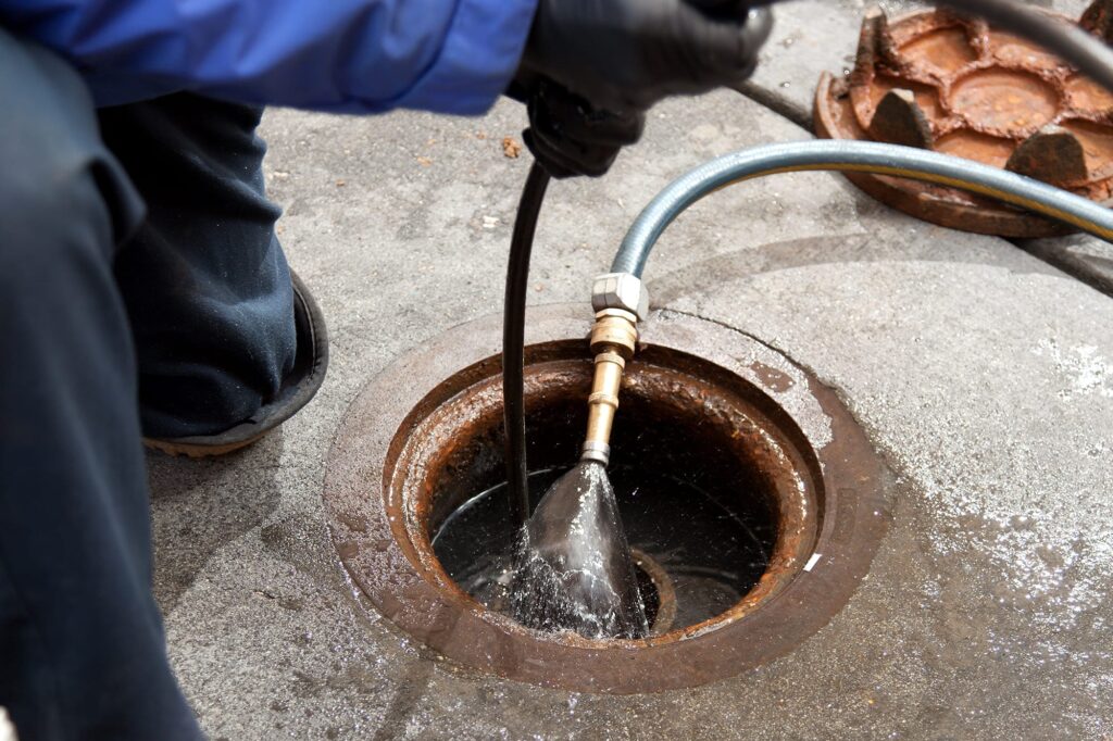 Plumber hydro jetting a sewer line through a manhole in Port Orange