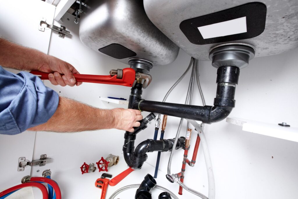 Plumber repairing drain pipes beneath a kitchen sink in Port Orange