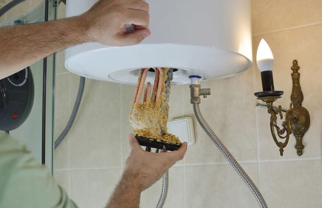 Technician removing mineral buildup from a water heater in Port Orange